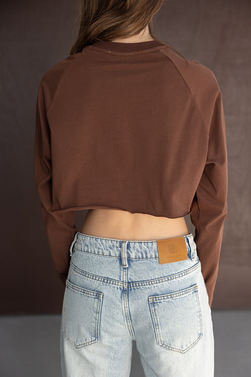 חולצת קרופ חומה עם שרוולים ארוכים, ג׳ינס בגזרה גבוהה בהירה, מבט גב על דוגמנית