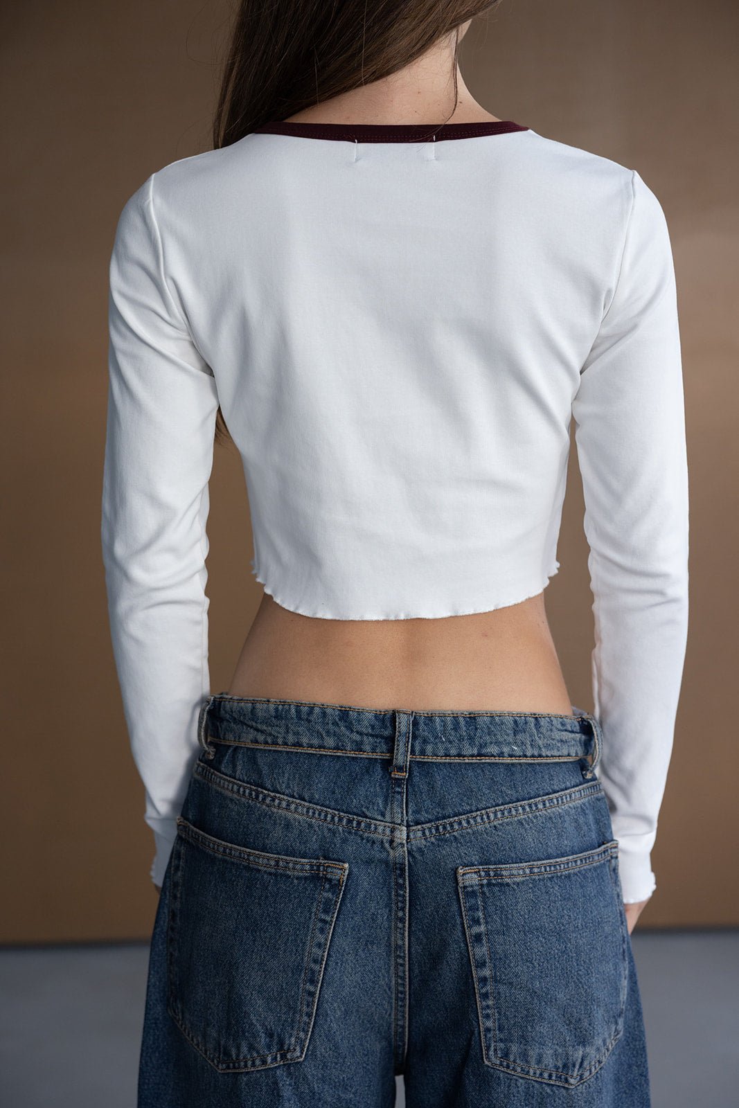 חולצת בייסיק לבנה ארוכה עם גזרה קצרה, מכנסי ג'ינס קלאסיים, תצוגת גב