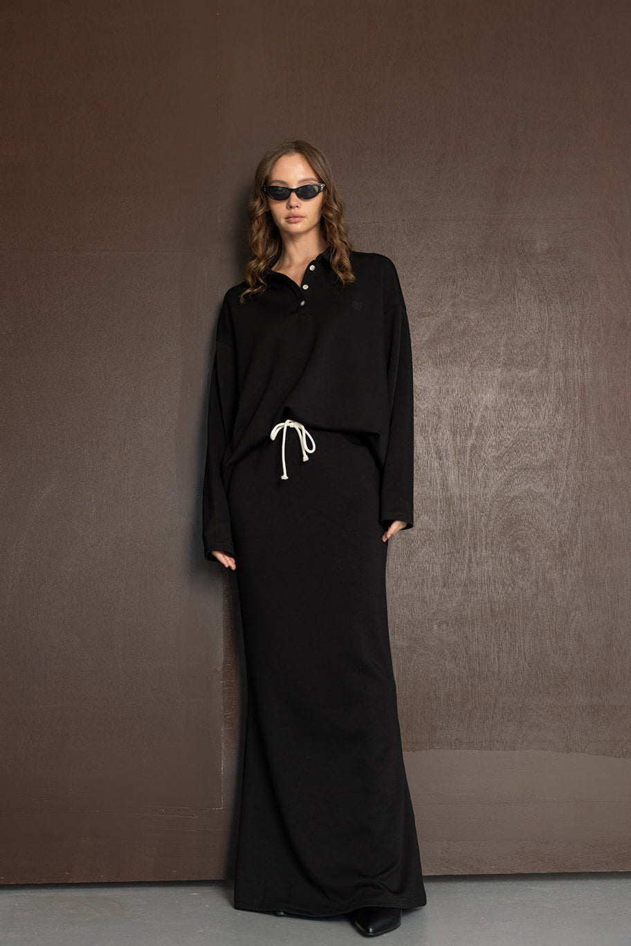 אישה לובשת שמלת מקסי שחורה עם שרוך לבן, משקפי שמש, אופנת נשים מודרנית