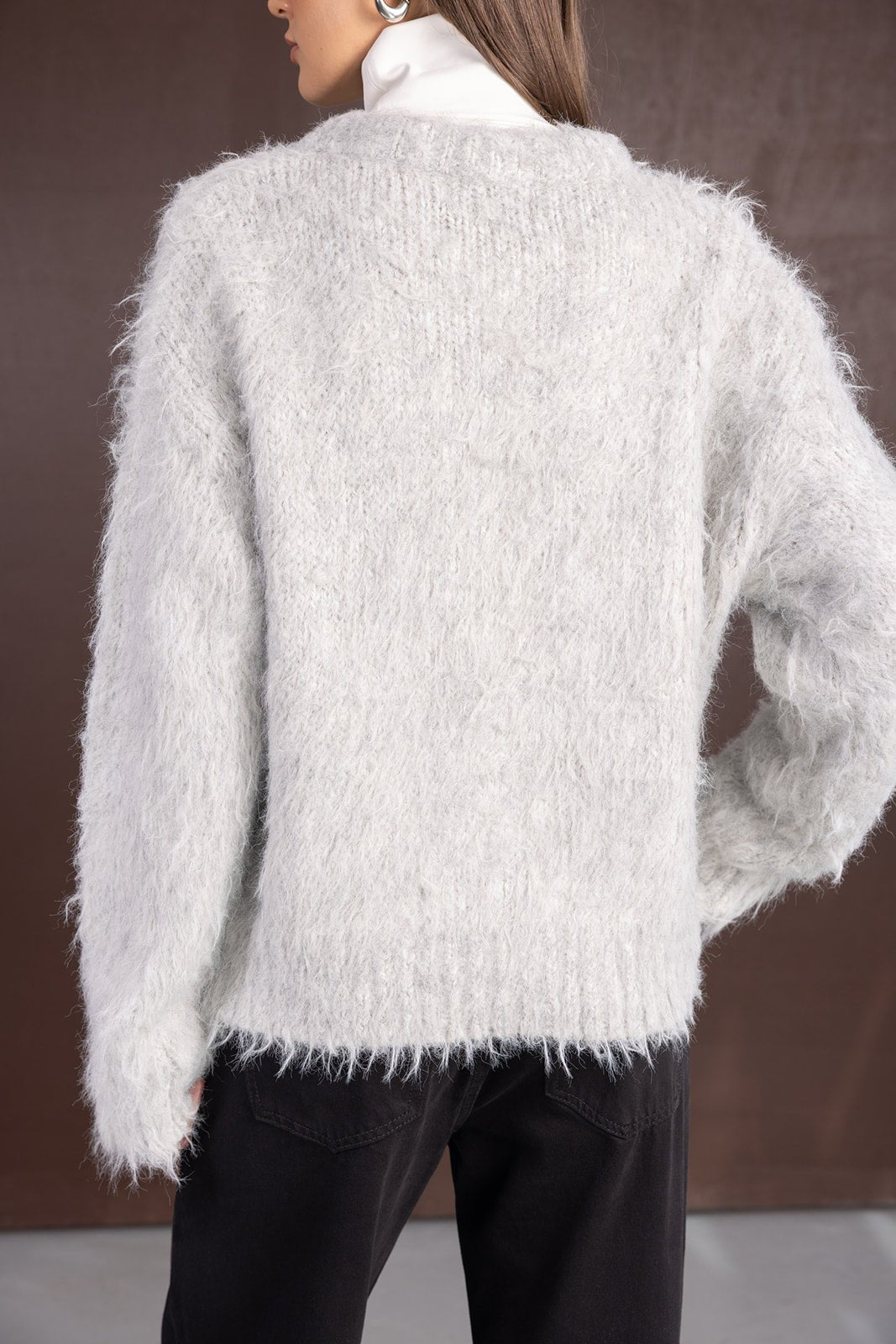 סריג נשים פלפי אפור עם שרוולים ארוכים, על גבי מכנסי ג'ינס כהים, צילום גב בסטודיו