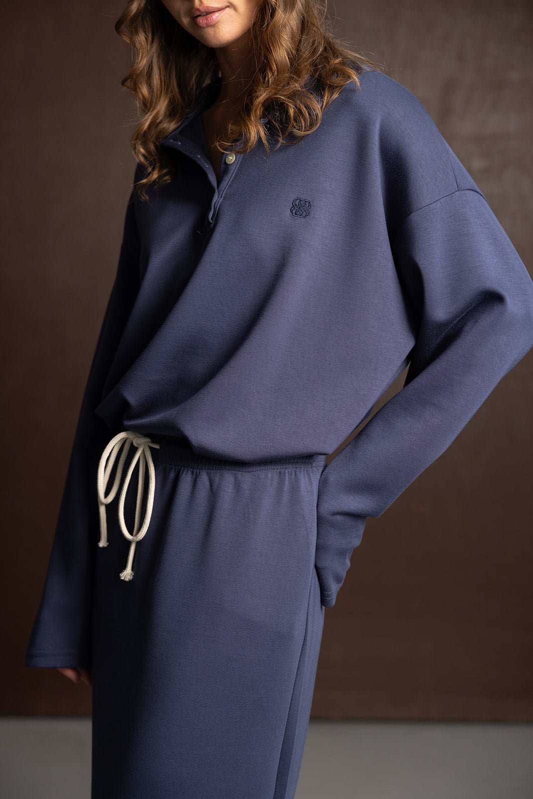 אישה לובשת סט טרנינג כחול כהה עם שרוך לבן, אופנת נשים ונערות, סט בגדים נוח ועדכני