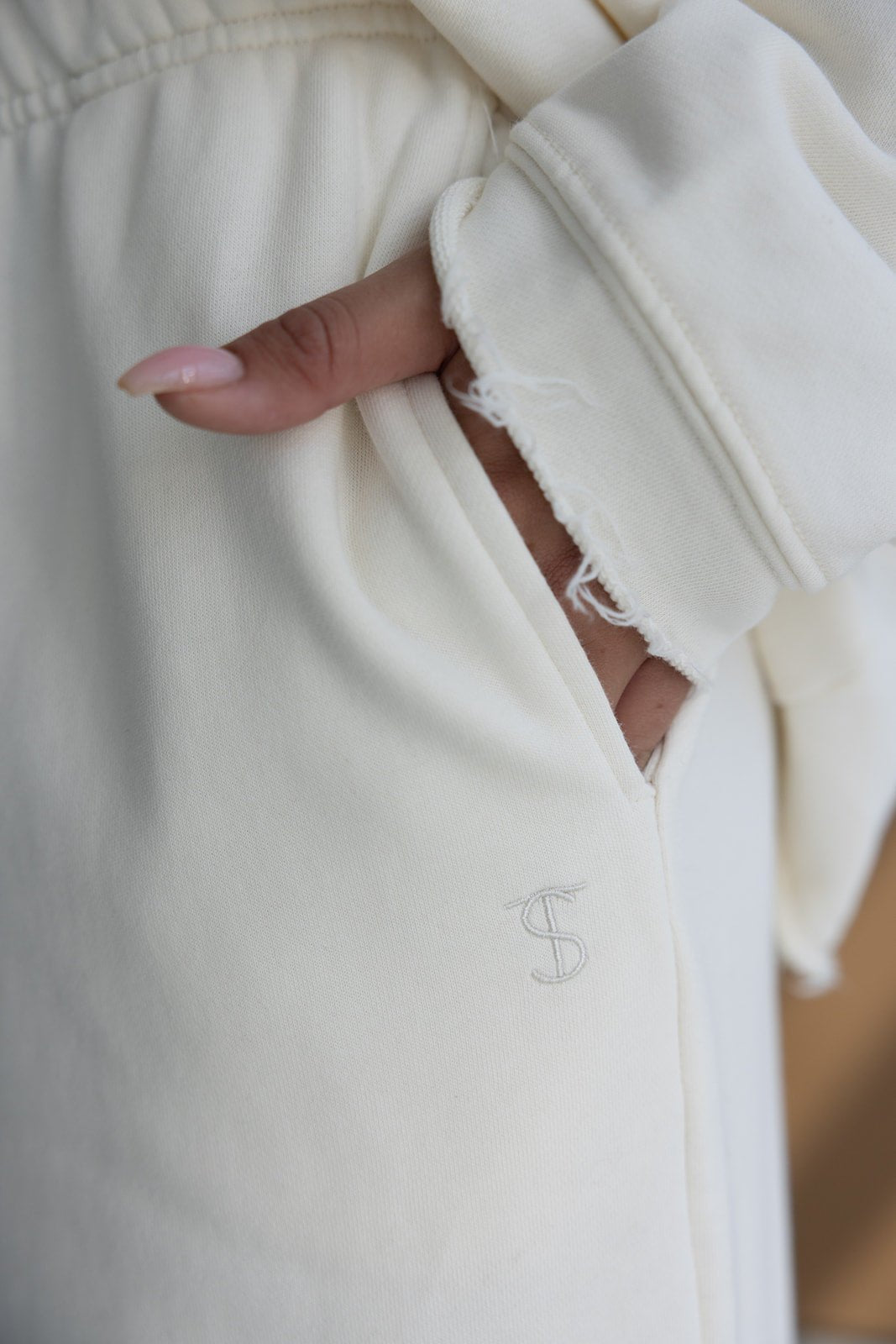 שרוול וחלק מכיס במכנסיים בגוון שמנת, מבד נעים, עם רקמת אותיות אופנתית ולוק קז'ואל לנשים