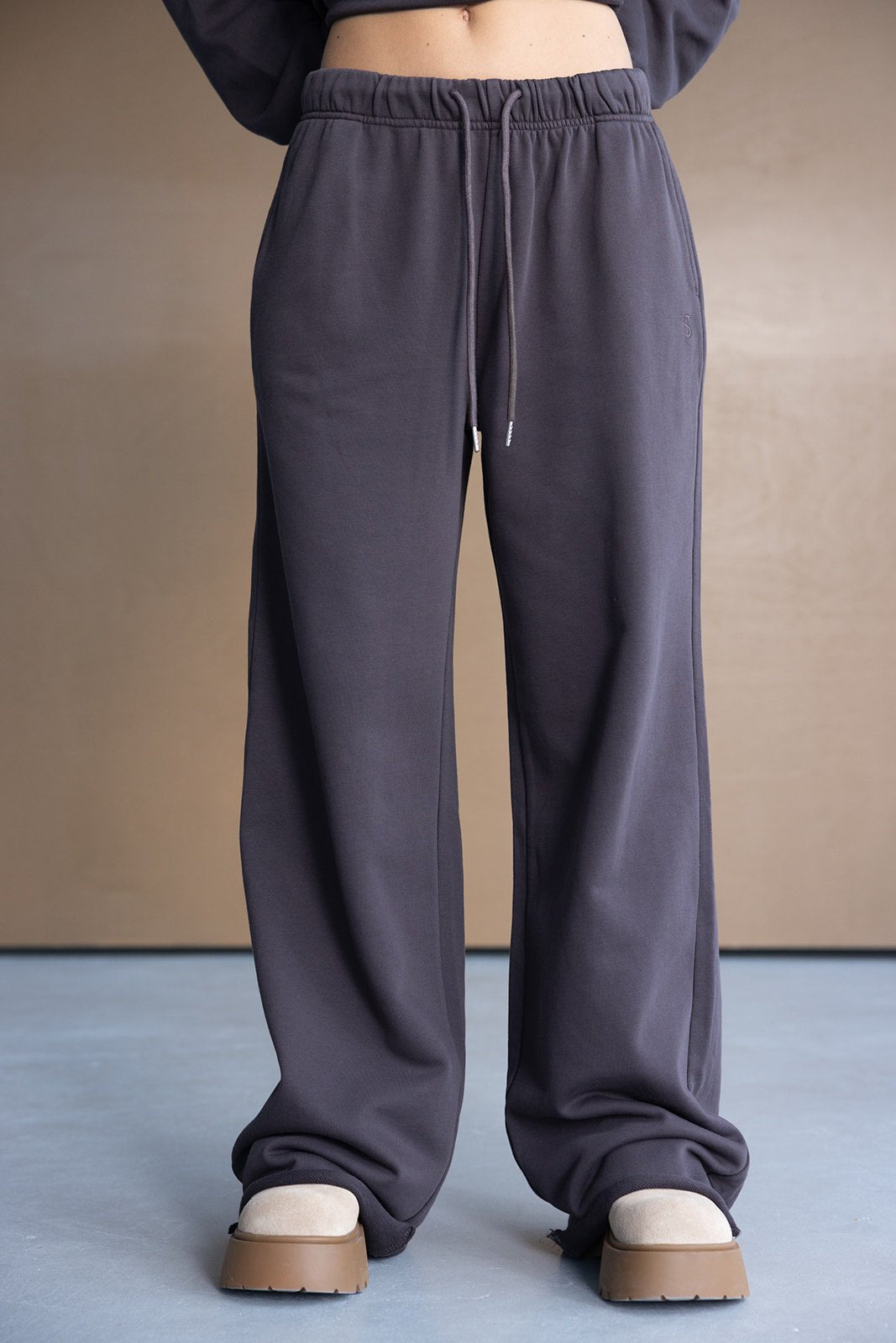 מכנסי טרנינג נשים בצבע אפור כהה, גזרה רחבה עם שרוך, נעלי פלטפורמה בז' אופנתיות