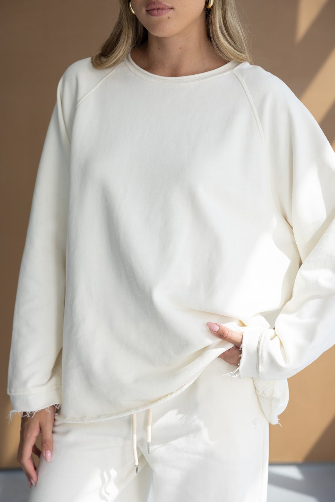 דוגמנית לובשת סווטשירט אופנתי לבן עם מכנסי טרנינג, ביגוד נוח לנשים, טרנד חורף 2024