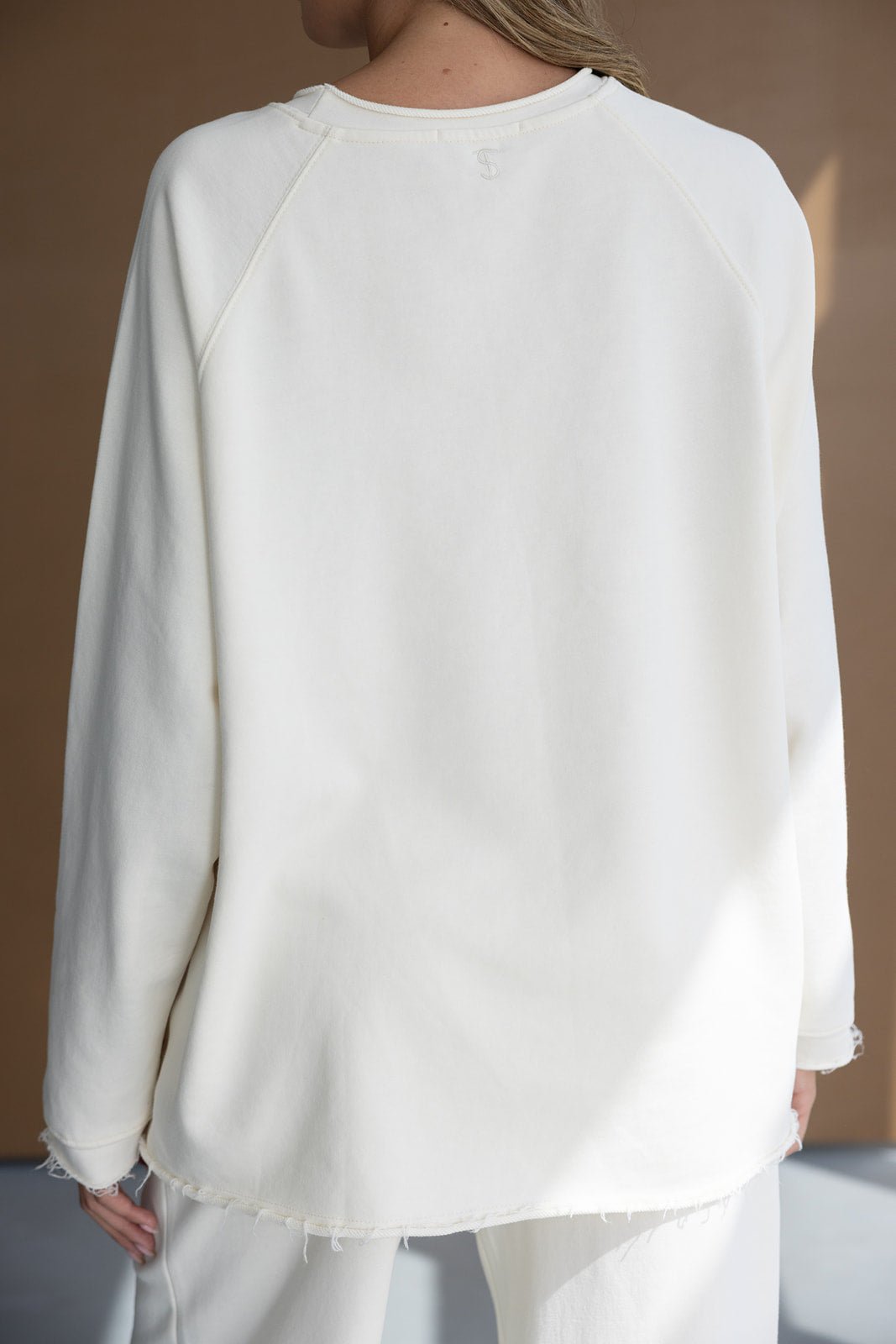 חולצת נשים ארוכה בגוון לבן עם תפרים גסים, מתאימה לאופנת קז'ואל צעירה