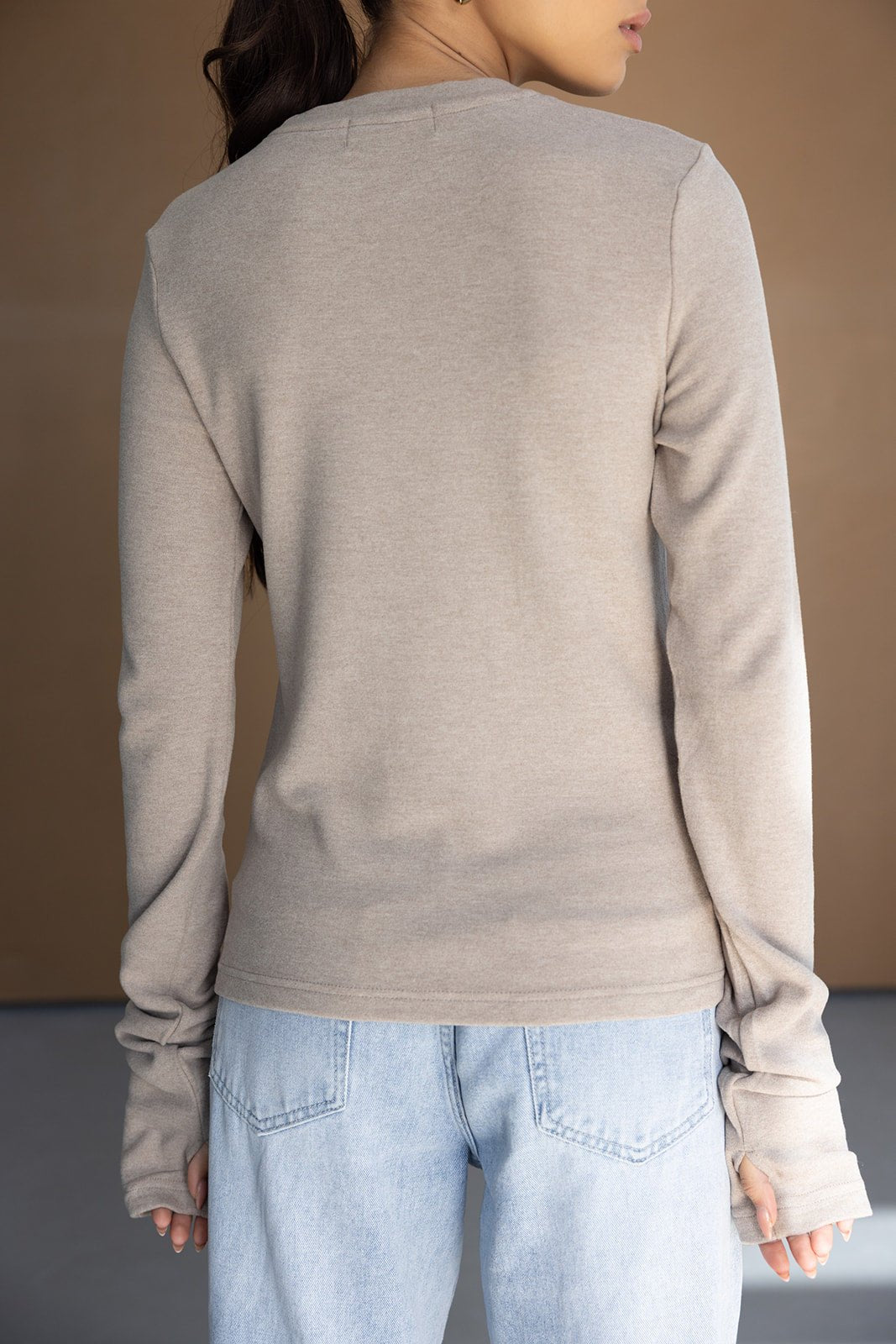 חולצה ארוכה לנשים בצבע בז' עם שרוולים ארוכים, משולבת עם ג'ינס בהיר, צילום מאחור