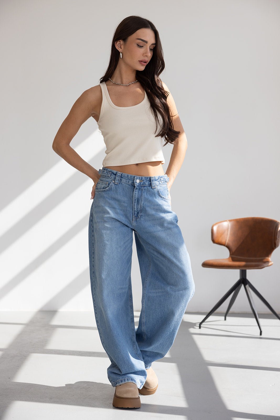 אישה עם גופיה לבנה ומכנסי ג'ינס רחבים, אופנת נשים צעירה בסגנון קז'ואל מודרני