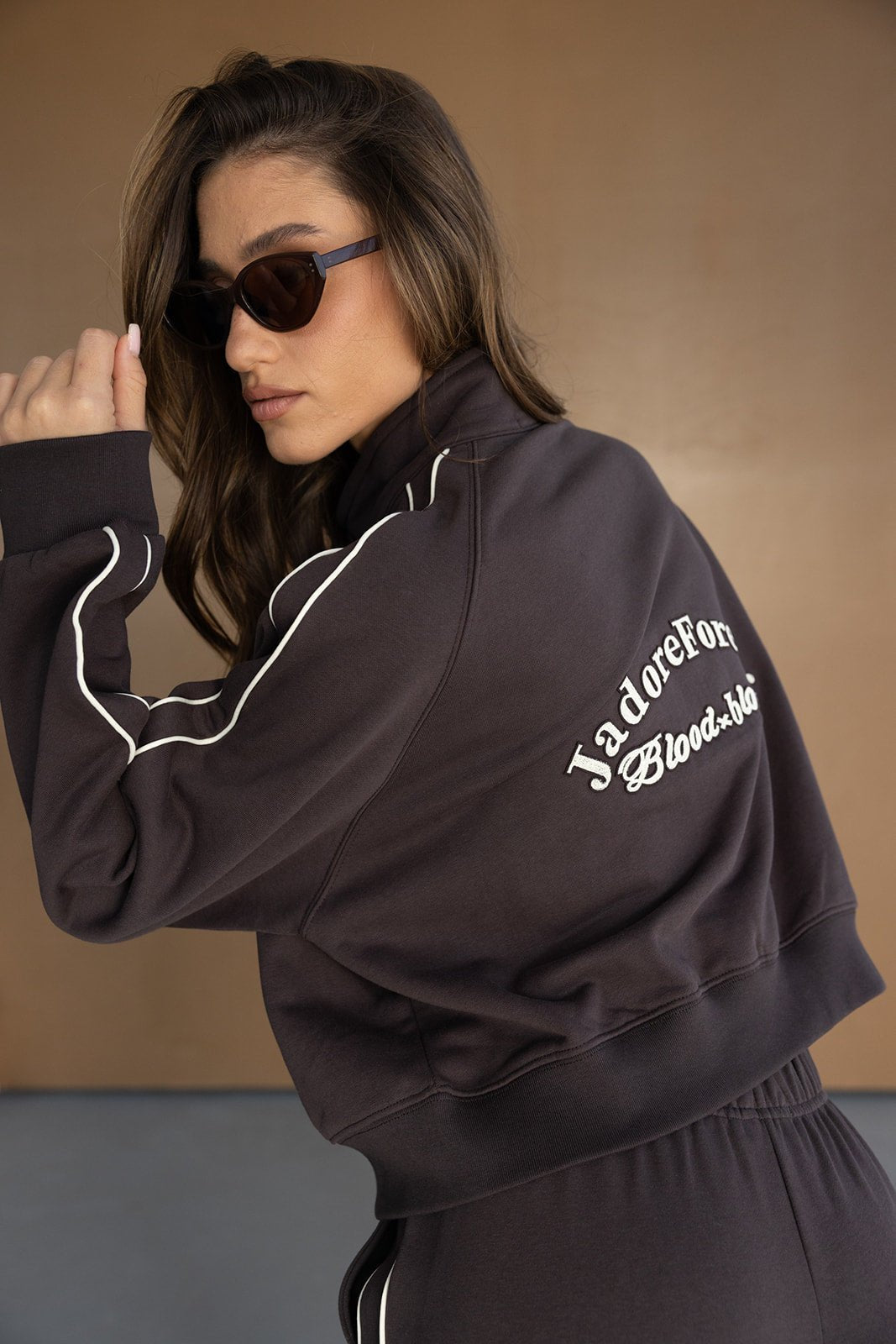 אישה עם חולצת טרנינג כהה וכיתוב, פסים לבנים ומשקפי שמש, אופנת נשים אופנתית