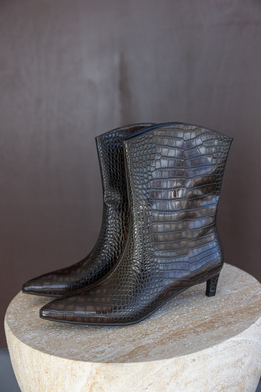 מגפי נשים חומים עם עקב נמוך, דמוי עור תנין, על רקע חום, אופנה טרנדית לנשים