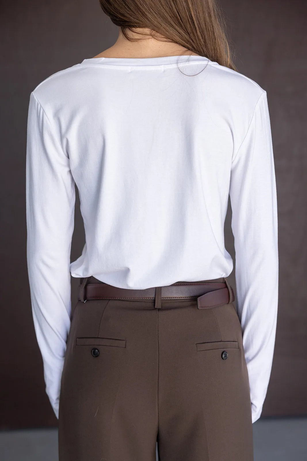 חולצת נשים לבנה עם שרוולים ארוכים ומכנסיים חומים מחויטים, מראה אופנתי קלאסי
