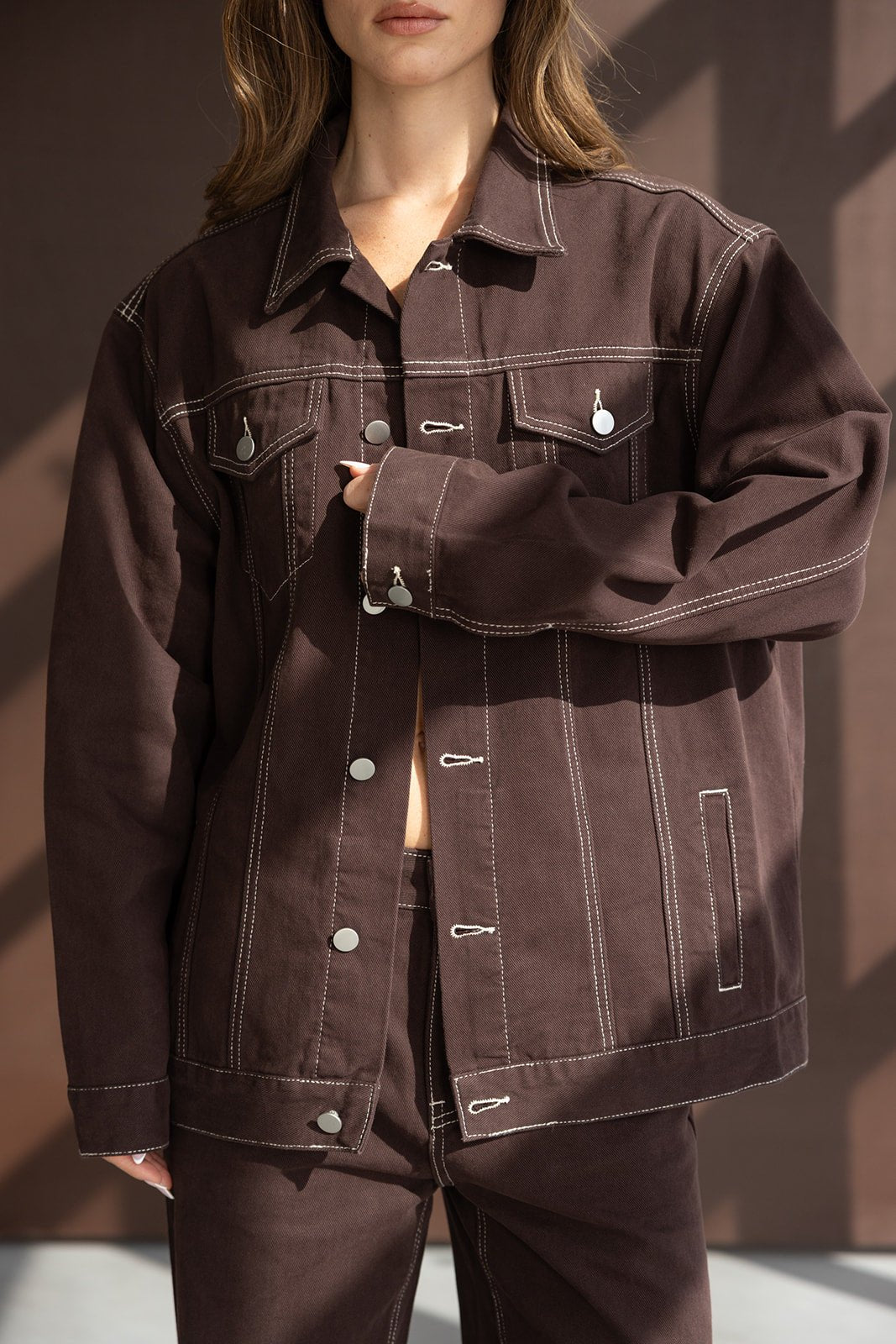 מעיל ג'ינס חום לנשים עם תפרים לבנים ודיטיילים בולטים, משולב עם מכנס תואם