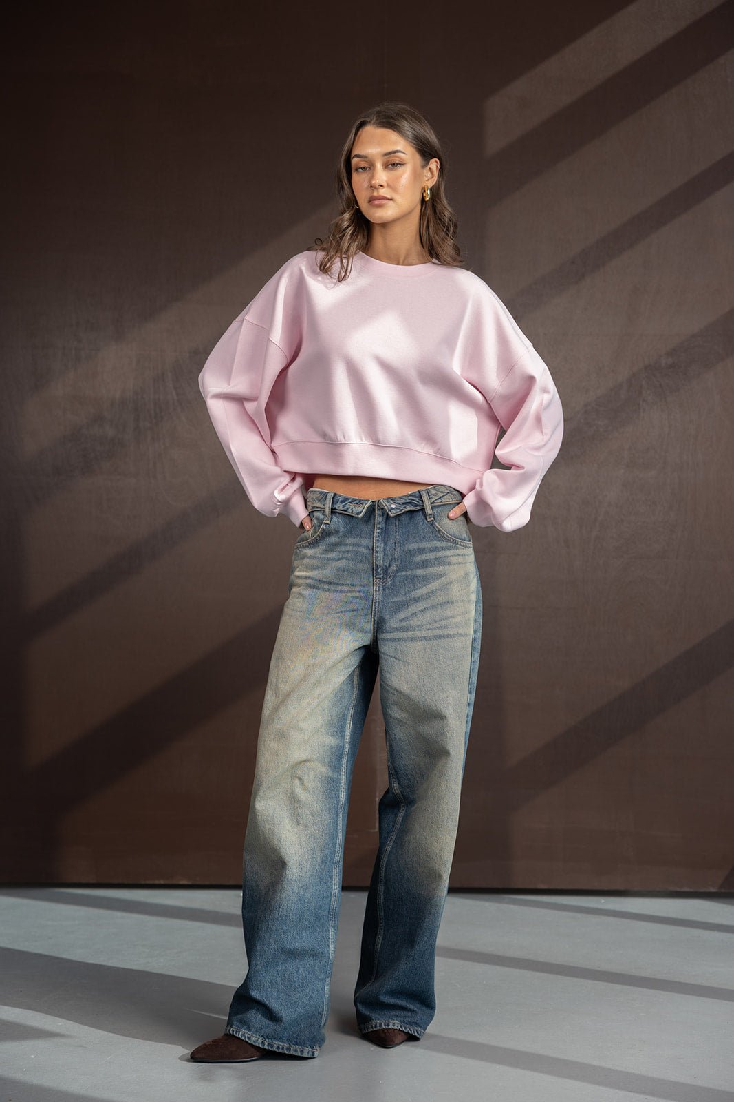דוגמנית לובשת סווטשירט ורוד קצר ומכנסי ג'ינס רחבים לנשים, אופנה צעירה וטרנדית