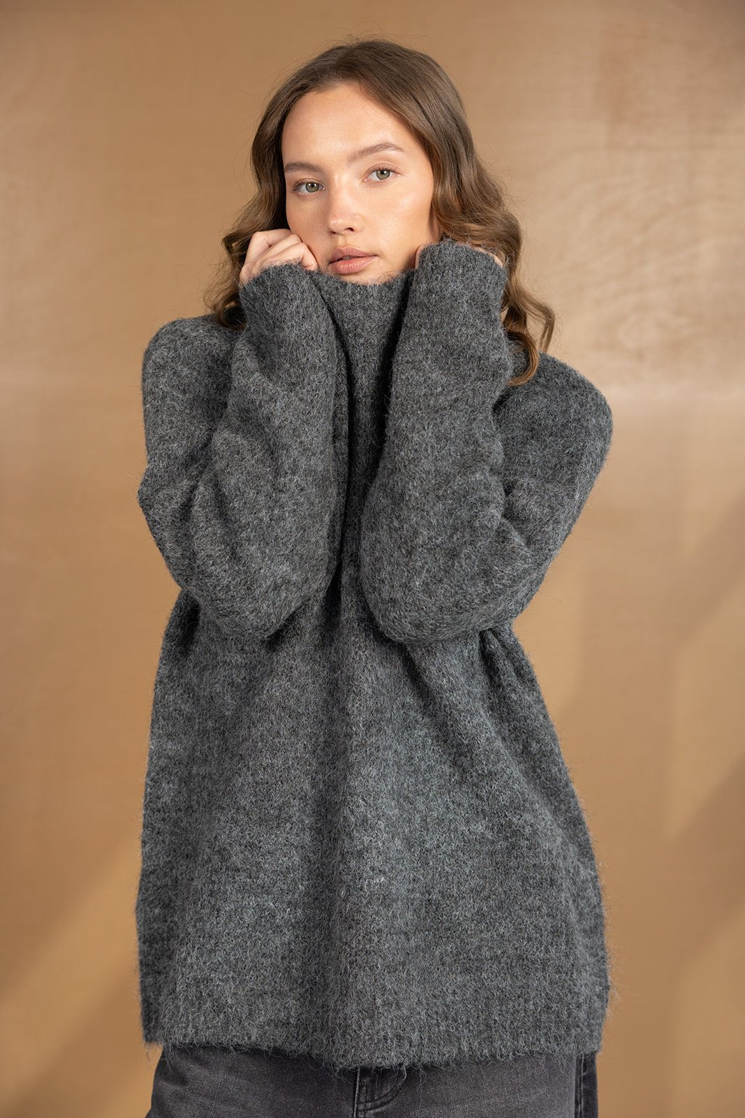 דוגמנית לובשת סוודר אפור צמרי לאופנת נשים, רקע חום, בגדי חורף לנערות