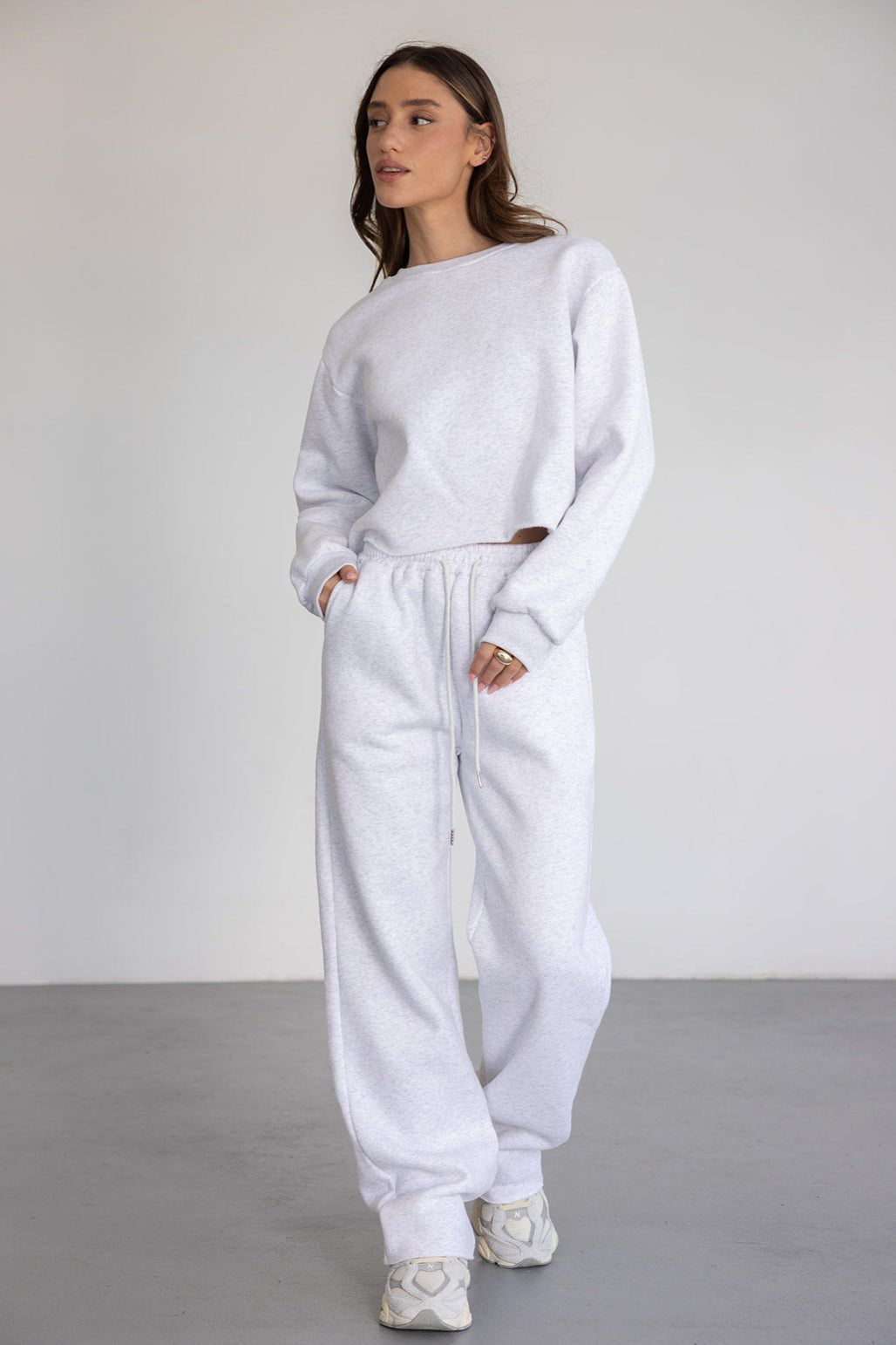 דוגמנית לובשת סט טרנינג אפור מחמיא לנשים, חולצה ארוכה ומכנסיים בגזרה רחבה ואופנתית