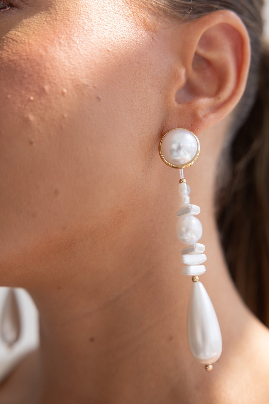 עגיל תלוי לאישה עם פנינה לבנה ועיצוב אלגנטי, תקריב על האוזן, תכשיטי אופנה לנשים