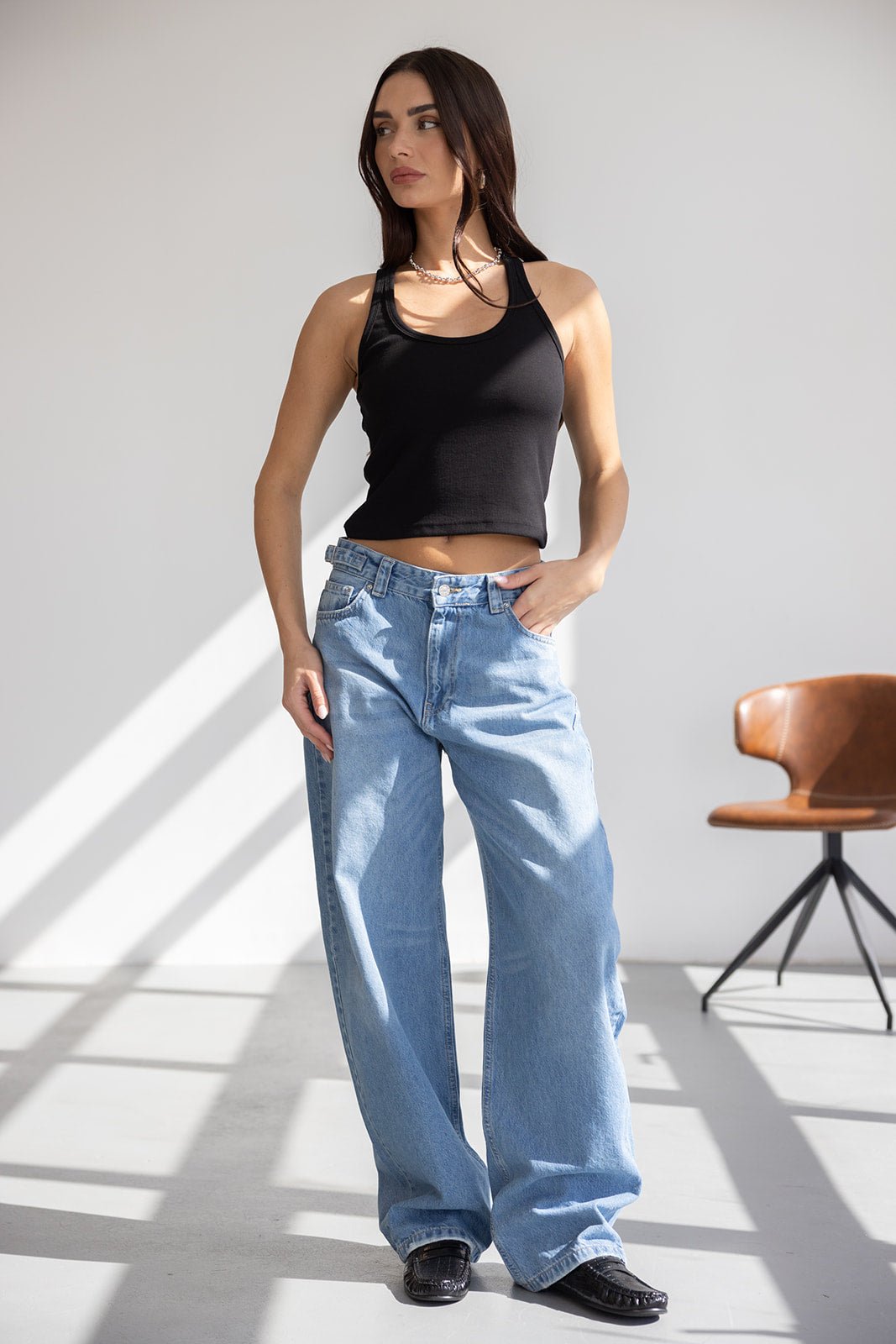 דוגמנית לובשת גופיית טופ שחורה ומכנסי ג'ינס רחבים בגזרה גבוהה, אופנת נשים טרנדית