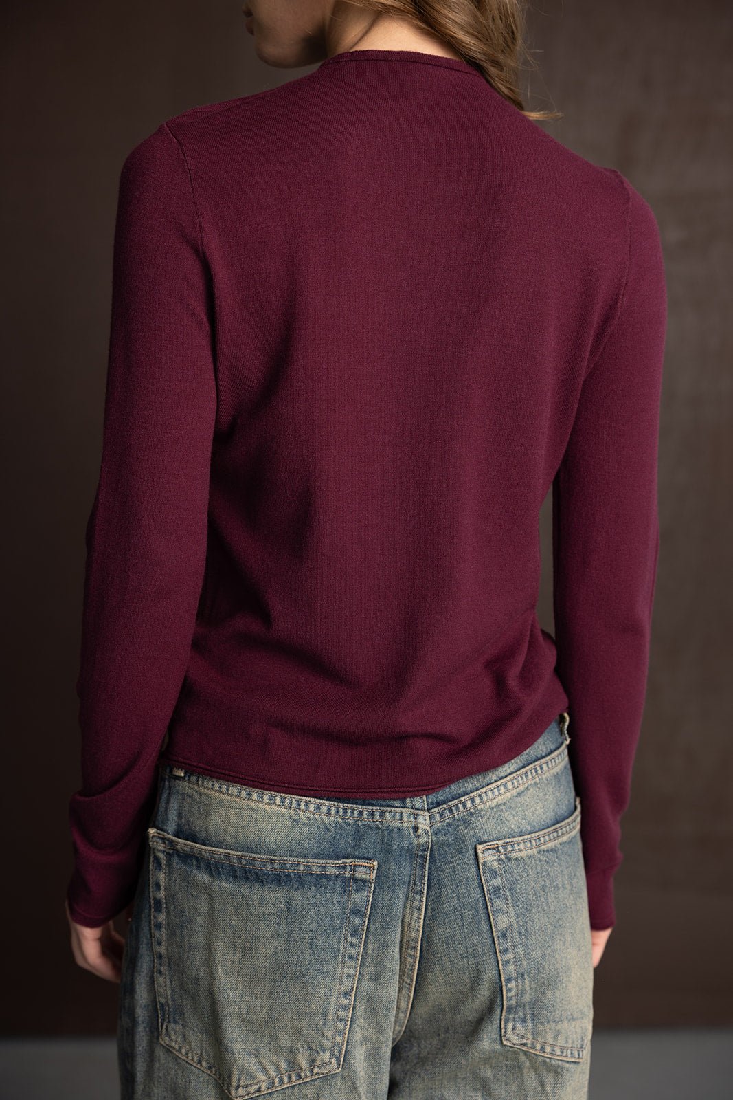חולצת נשים ארוכת שרוולים צבע בורדו בשילוב ג’ינס עם כיסים גדולים, צילום אופנה מאחור