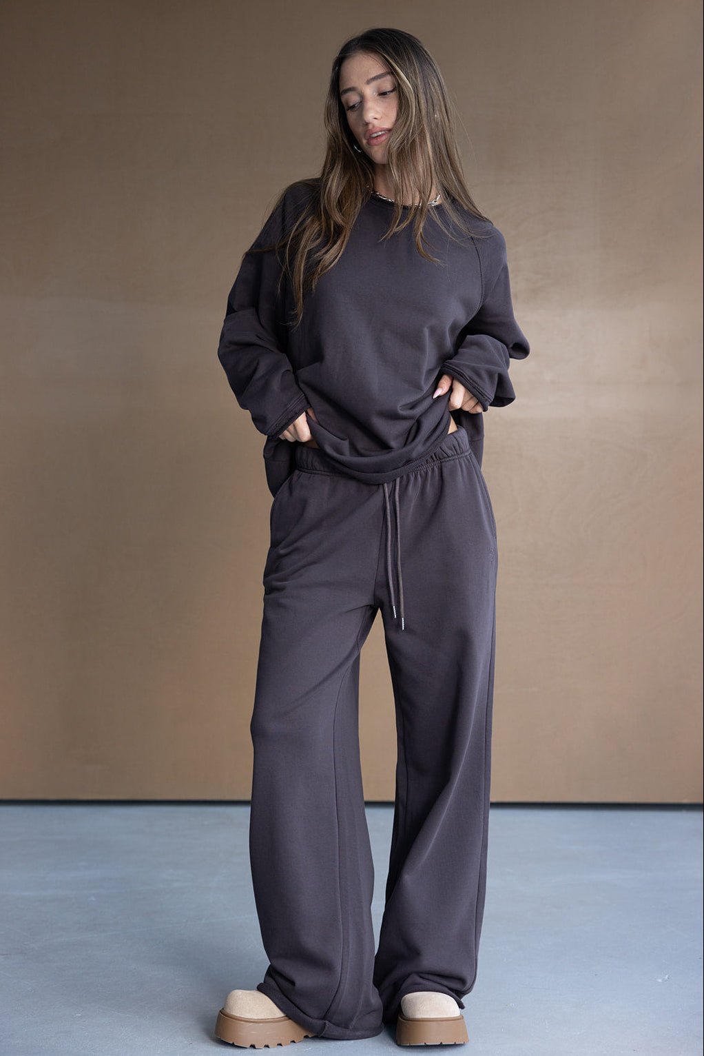 דוגמנית לובשת סט טרנינג רחב לנשים בצבע כהה, חולצה ומכנסיים תואמים, אופנה לנערות