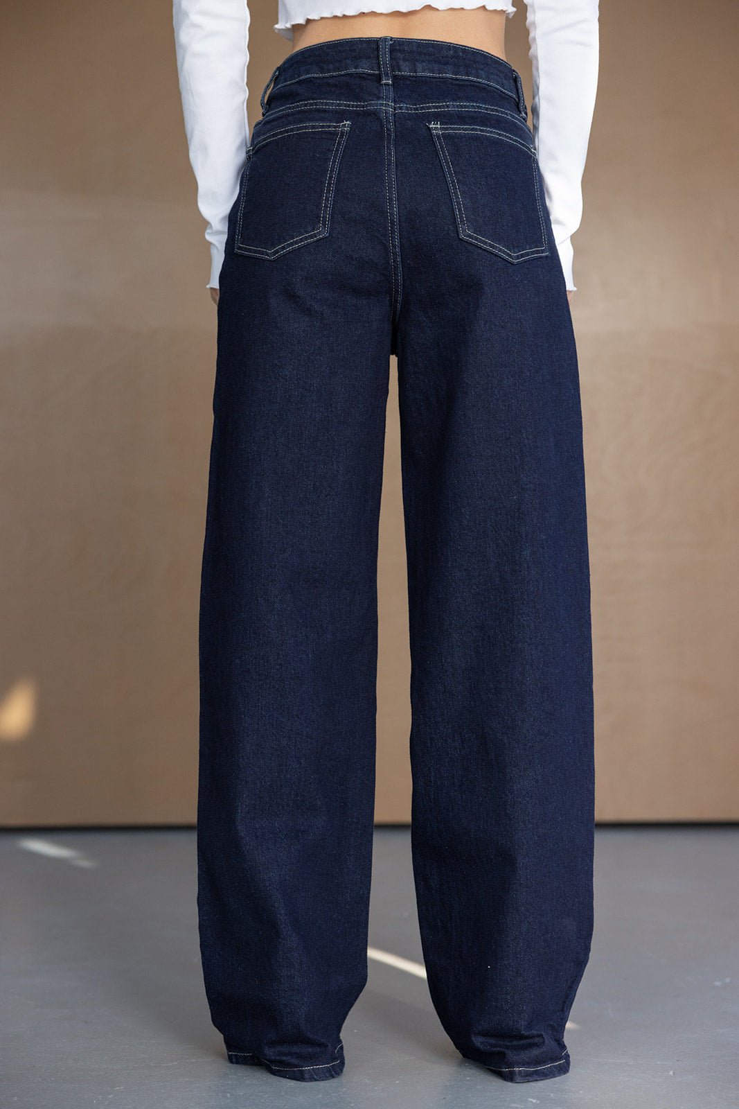 מכנסי ג'ינס כהים לנשים בגזרת רגל רחבה, רקע ניטרלי, אופנת קז'ואל לנערות