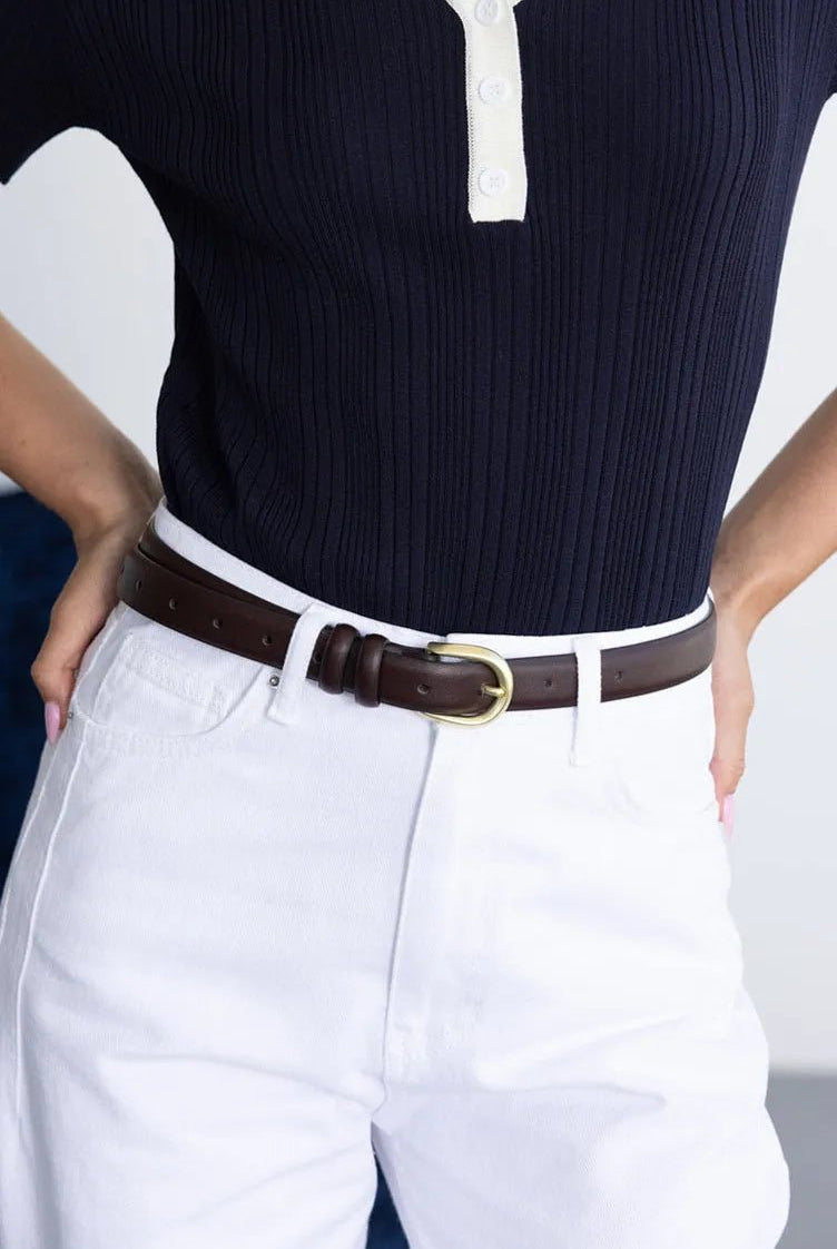 מכנסי ג׳ינס לבנים לנשים עם חולצת פסים כהה וחגורת עור חומה עם אבזם זהב