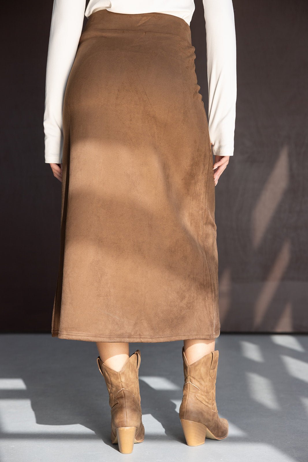 חצאית מידי חומה לנשים מבד זמש, עם חולצה ארוכה לבנה ונעלי בוקרים חומות