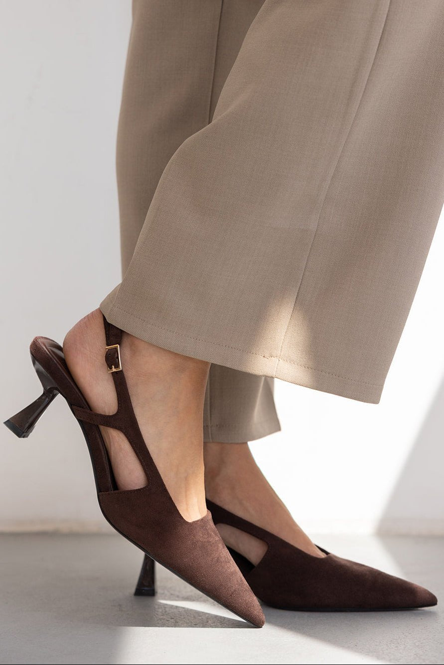 נעלי עקב חומות לנשים עם רצועה ובד זמש, משולבות עם מכנסיים רחבים בצבע בז'.