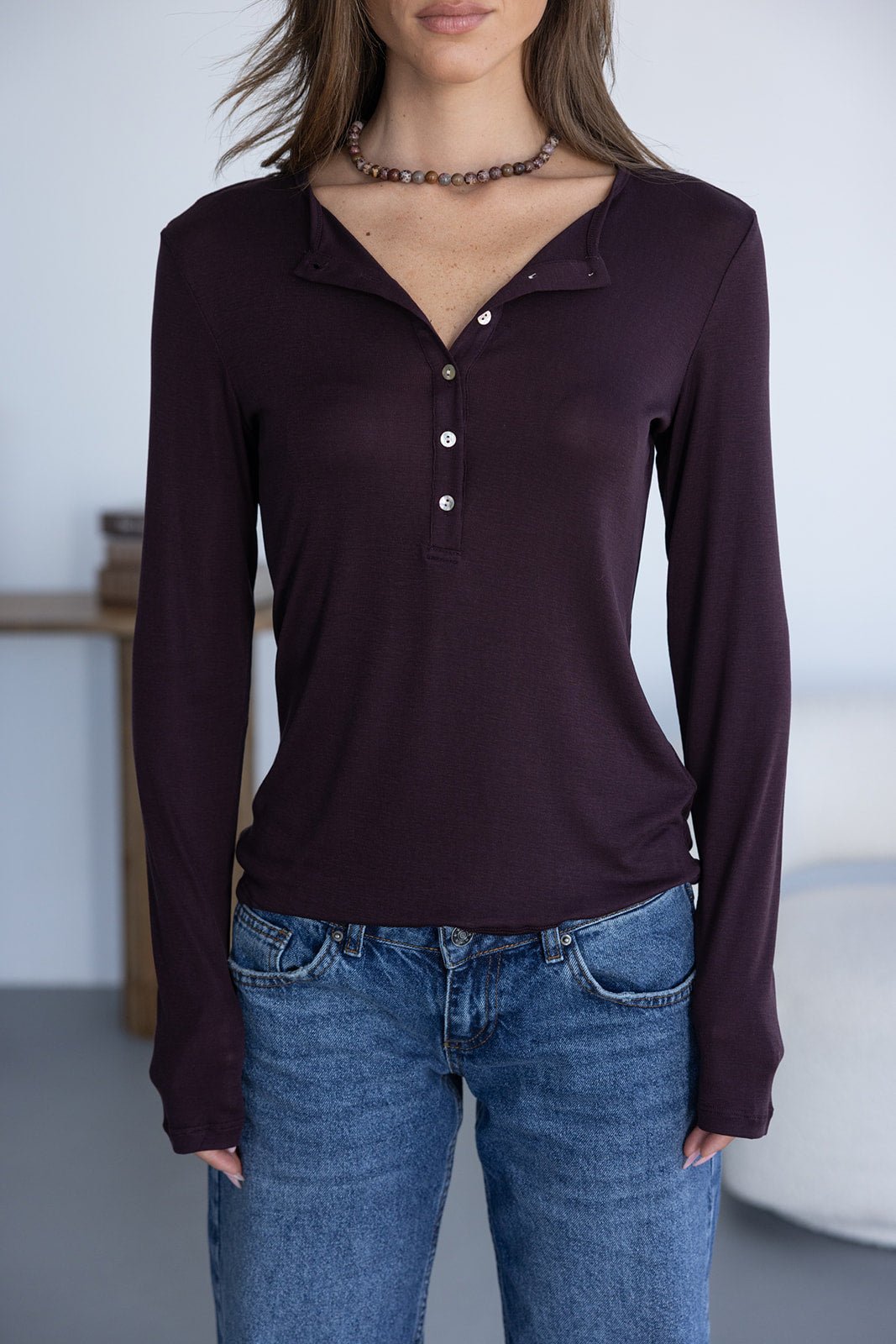 חולצת בייסיק ארוכה בצבע בורדו עם כפתורים, על דוגמנית שלבושה בג'ינס קז'ואל