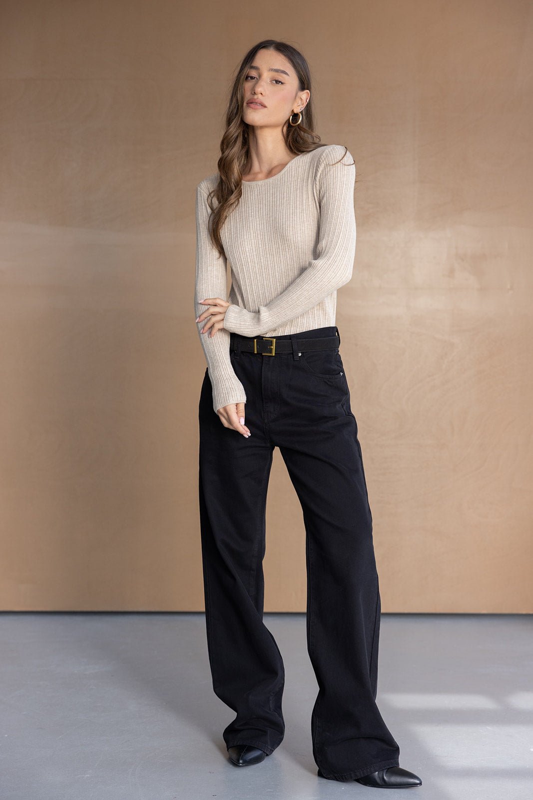 דוגמנית לובשת סוודר בז' עם שרוולים ארוכים ומכנסיים רחבים שחורים, אופנה נשית קז'ואל