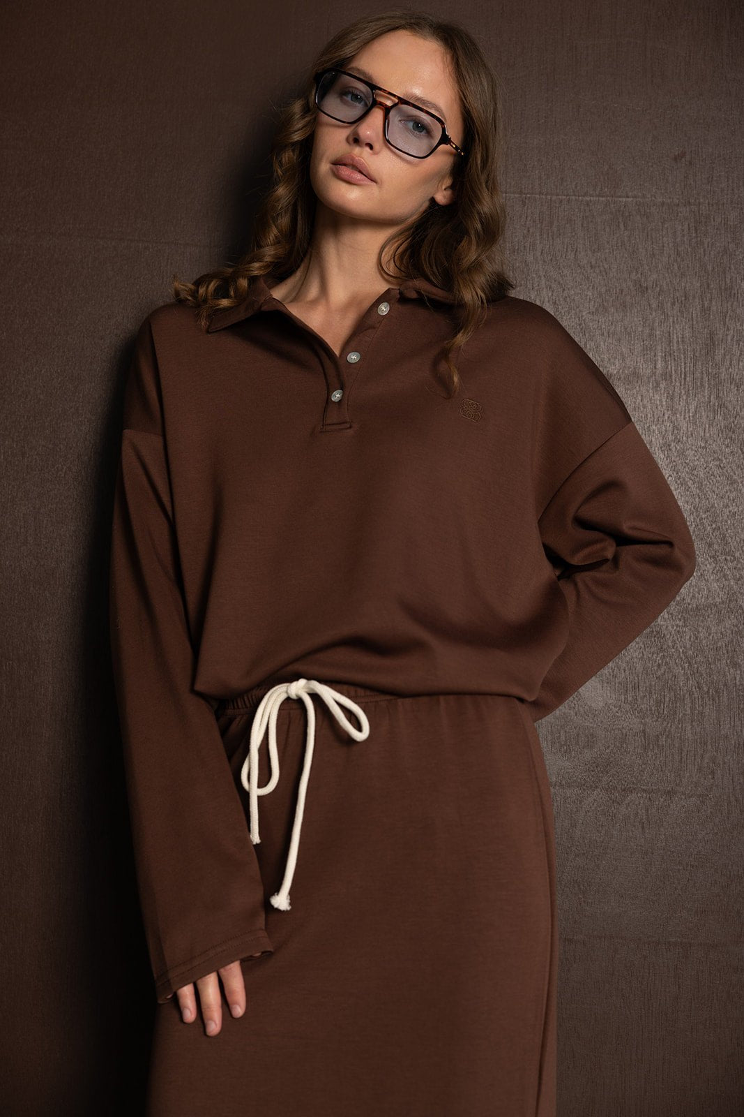 אישה עם שמלת קז'ואל חומה עם שרוך לבן, משקפיים גדולים, טרנד אופנה לנשים צעירות