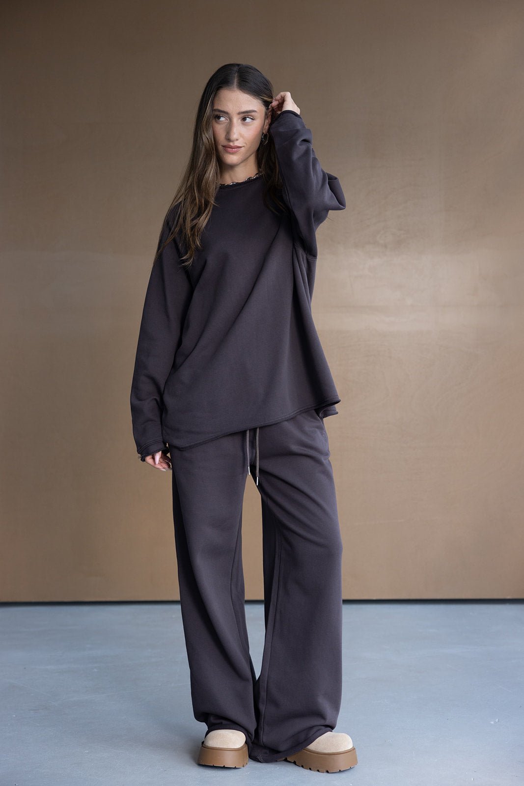 דוגמנית לובשת חליפת טרנינג נשים בצבע כהה עם מכנסיים רחבים וסווטשירט, אופנה לנערות