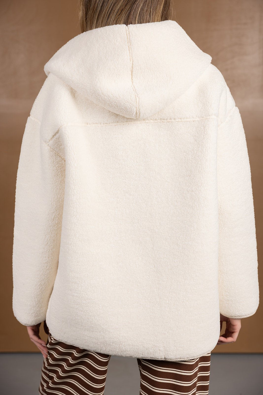 מעיל נשים לבן מבד פליז עם קפוצ'ון, מצולם מאחור, בגדי חורף אופנתיים