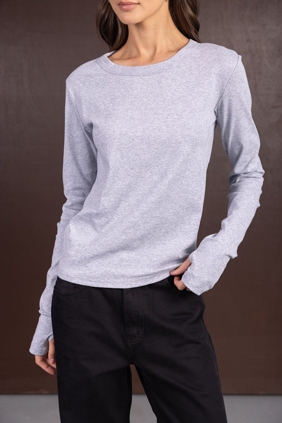 דוגמנית לובשת חולצת טריקו אפורה ארוכת שרוולים ומכנסיים שחורים, אופנת נשים צעירה