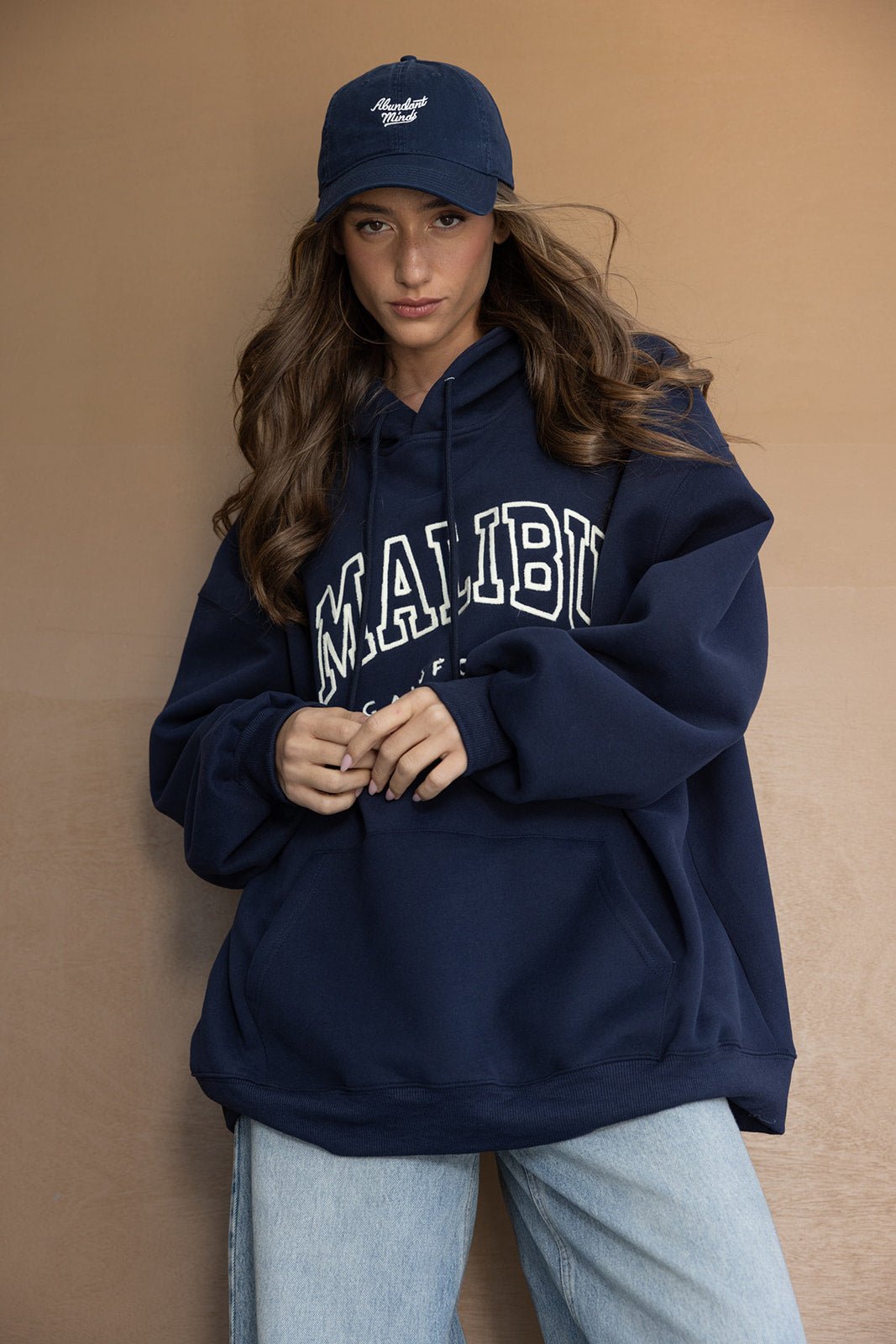 דוגמנית לובשת קפוצ'ון כחול עם כיתוב 'MALIBU' וכובע מצחייה, לוק אופנתי לנשים