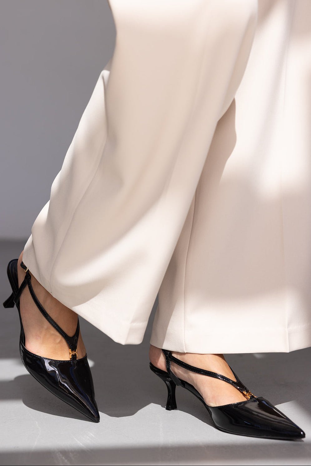 נעליים שחורות עקב נמוך עם רצועה, נעלי נשים אלגנטיות לצד מכנסיים רחבים בצבע שמנת