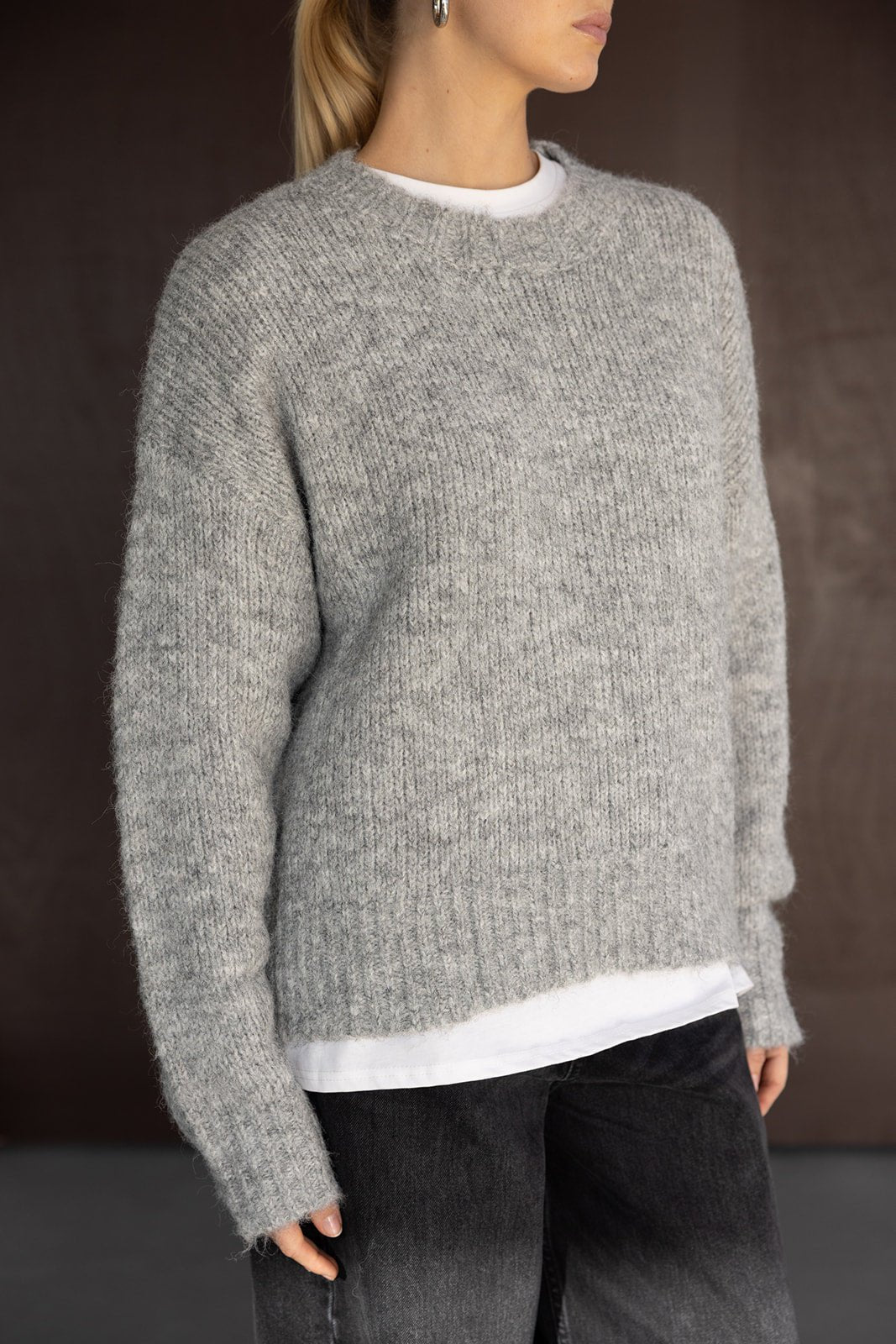 סוודר נשים אפור עם מרקם צמר, גזרה רחבה, משולב עם חולצה לבנה ומכנסי ג'ינס שחורים