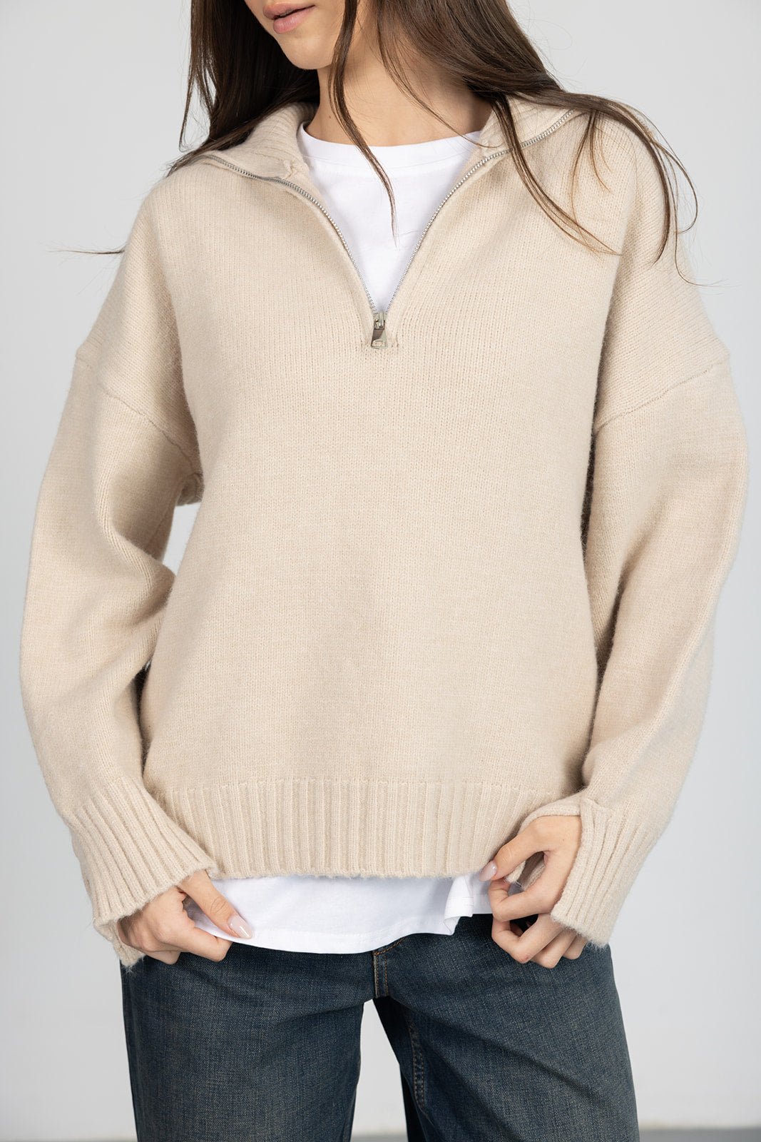 סוודר בז' לנשים עם רוכסן בחזה, חולצה לבנה מתחת וג'ינס, אופנת חורף לנערות