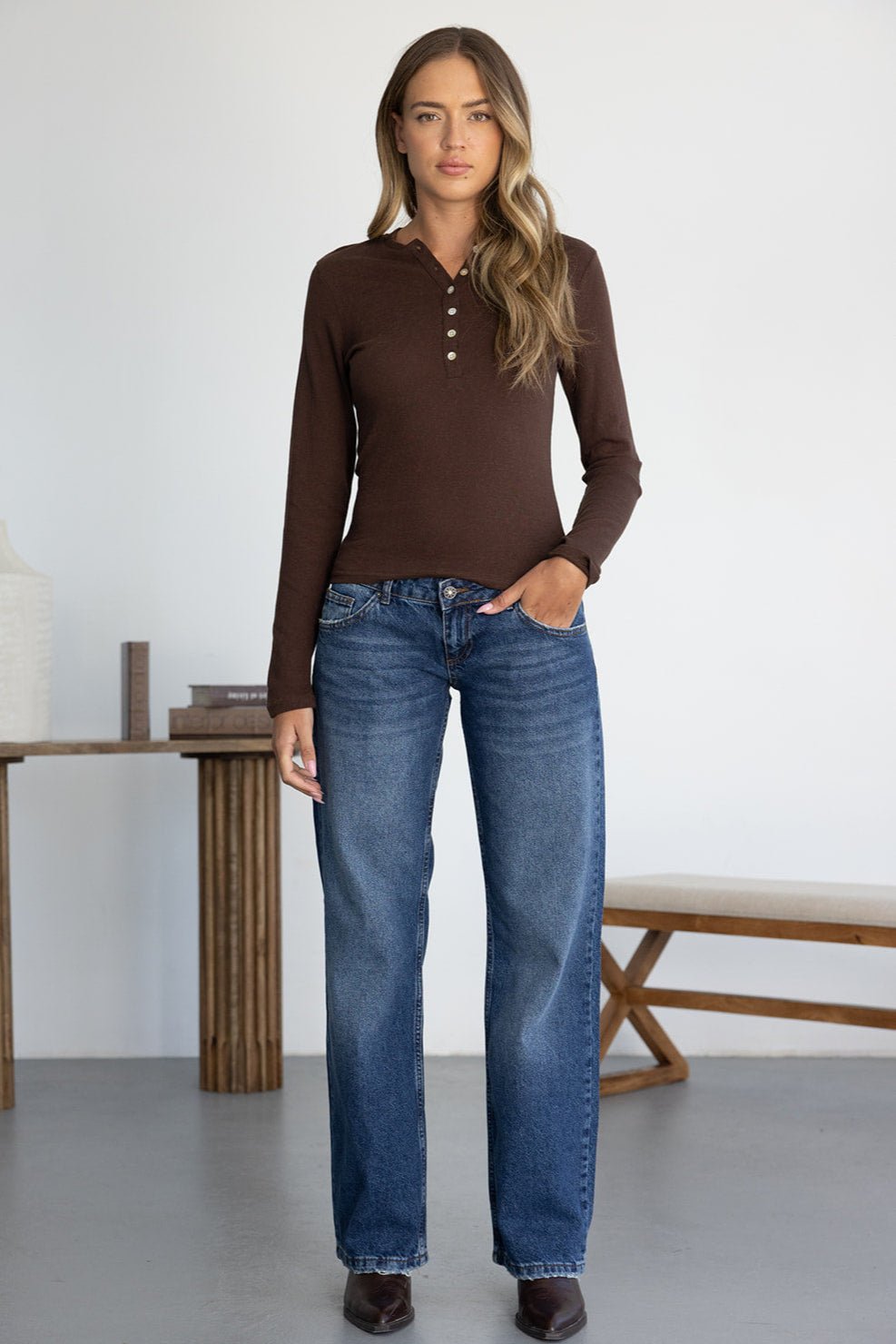 אישה לובשת חולצה חומה עם כפתורים ומכנסי ג'ינס בגזרה רחבה, אופנת נשים ונערות עדכנית