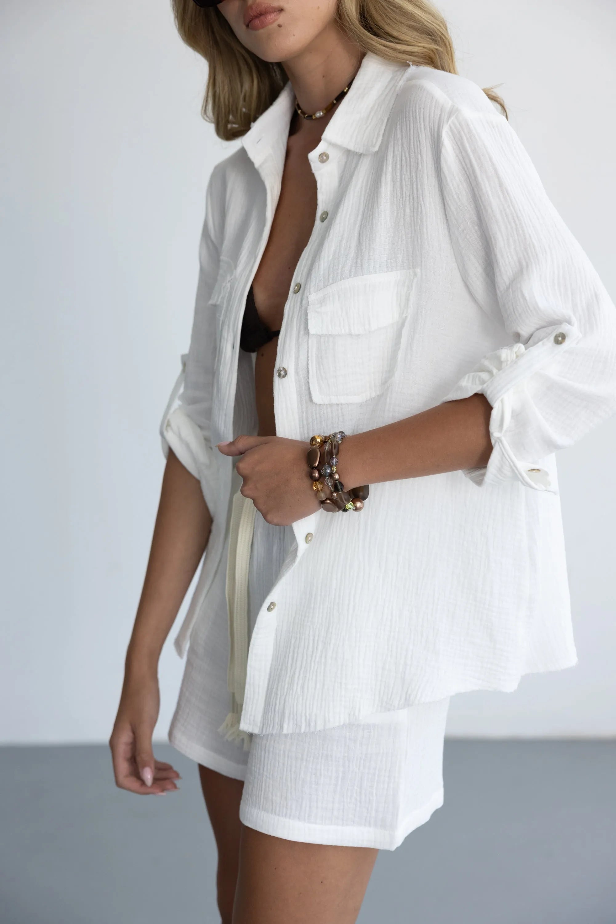 דוגמנית לובשת חולצה מכופתרת לבנה ומכנסיים קצרים, אופנת קיץ לנשים