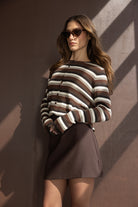 דוגמנית עם סוודר פסים חום לבן חצאית חומה ומשקפי שמש אופנה לנשים