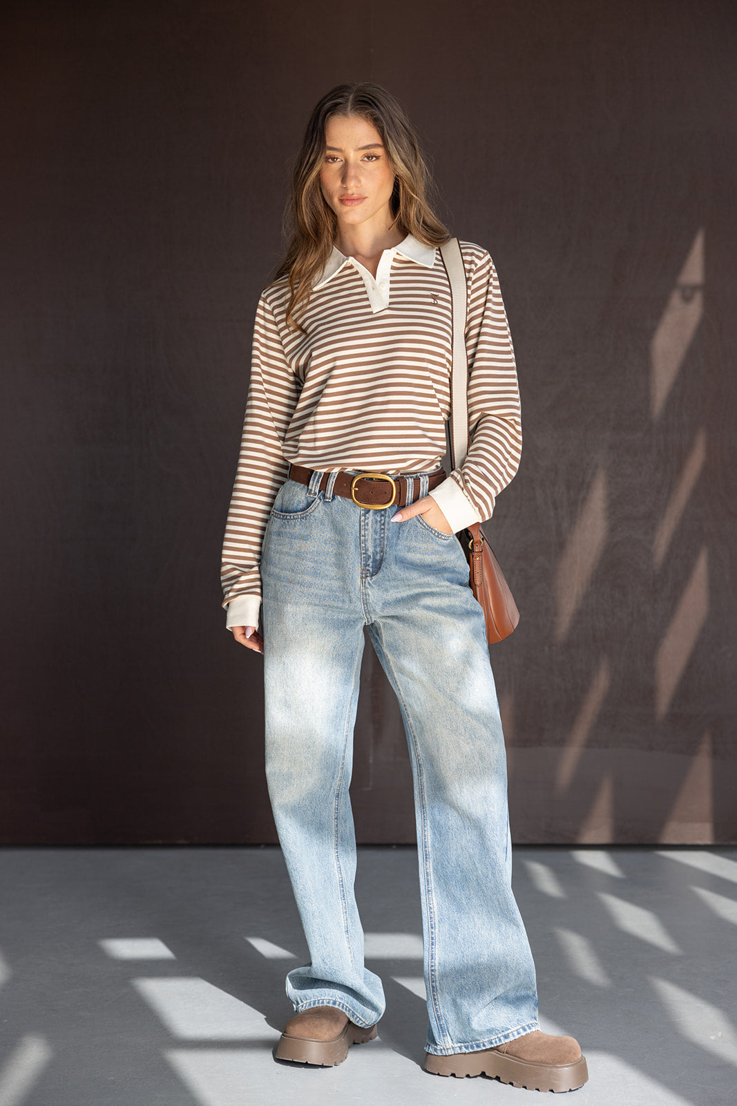 אישה לובשת חולצת פסים חומה ולבנה עם צווארון, ג'ינס רחב ונעלי סוליה עבה, אופנת נשים צעירה