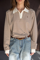חולצת פסים חומה ולבנה עם שרוולים ארוכים וצווארון, משולבת עם ג'ינס כחול רחב, אופנת נשים