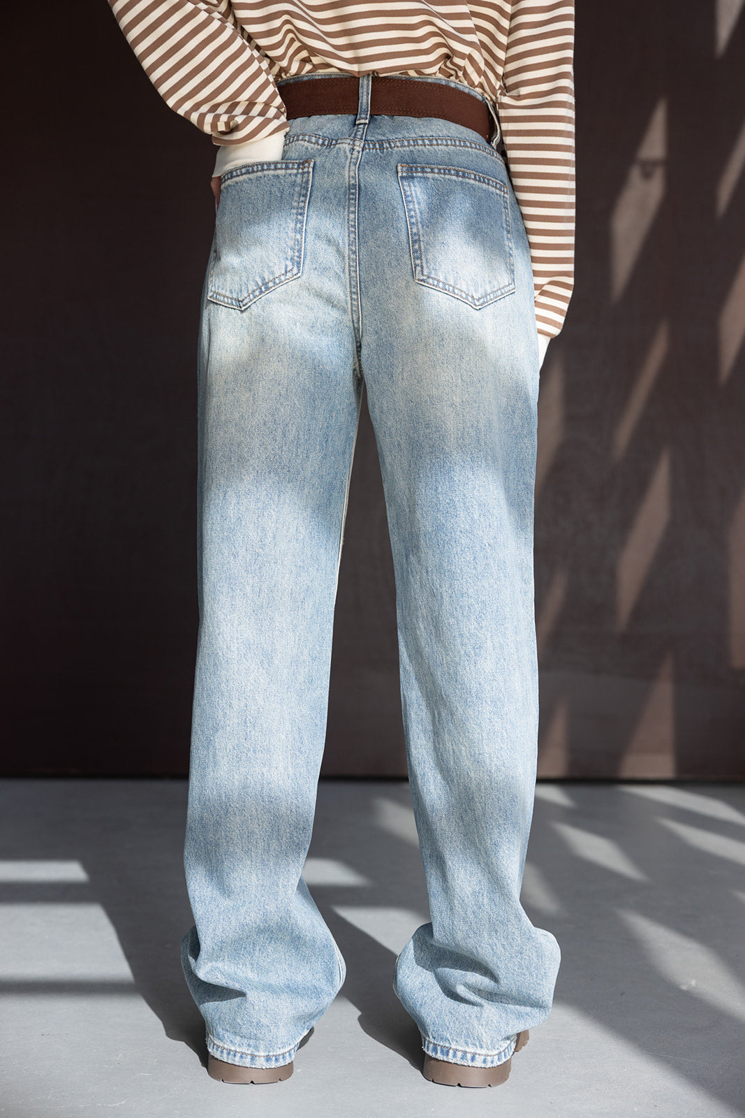 ג'ינס נשים בגזרה רחבה צבע תכלת עם חגורה חומה, חולצה פסים חומה-לבנה, צילום חוץ