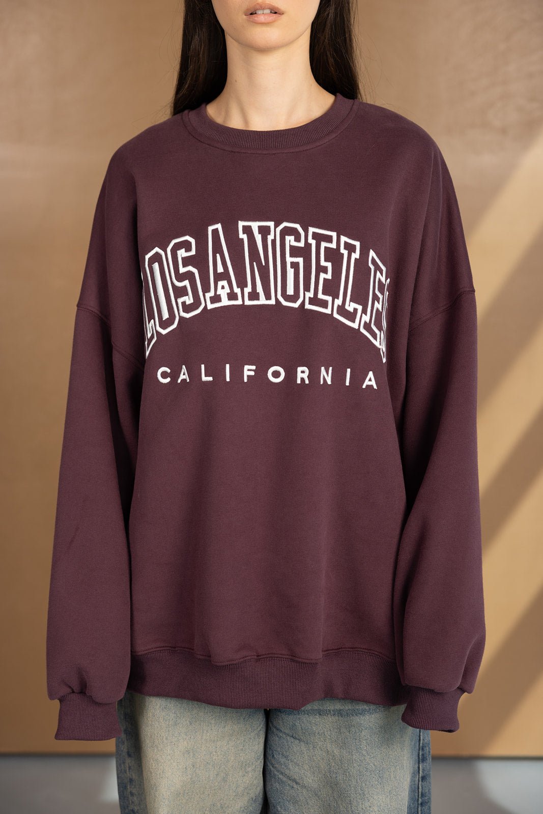 אישה עם סווטשירט בורדו עם כיתוב 'LOS ANGELES CALIFORNIA', אופנת רחוב לנשים