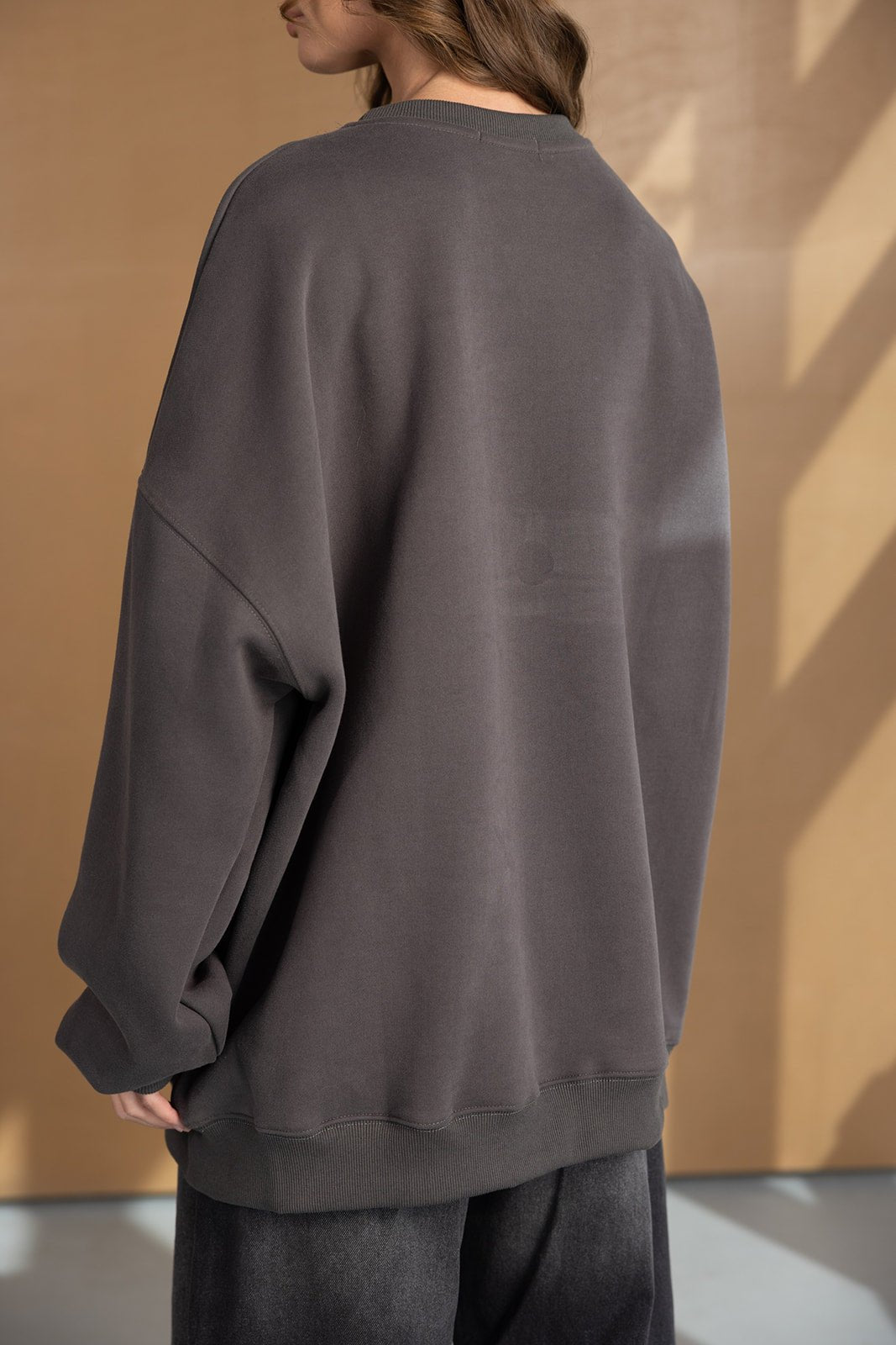 אישה לובשת סווטשירט אפור אוברסייז לנשים, צילום מאחור, אופנה נוחה ליום יום