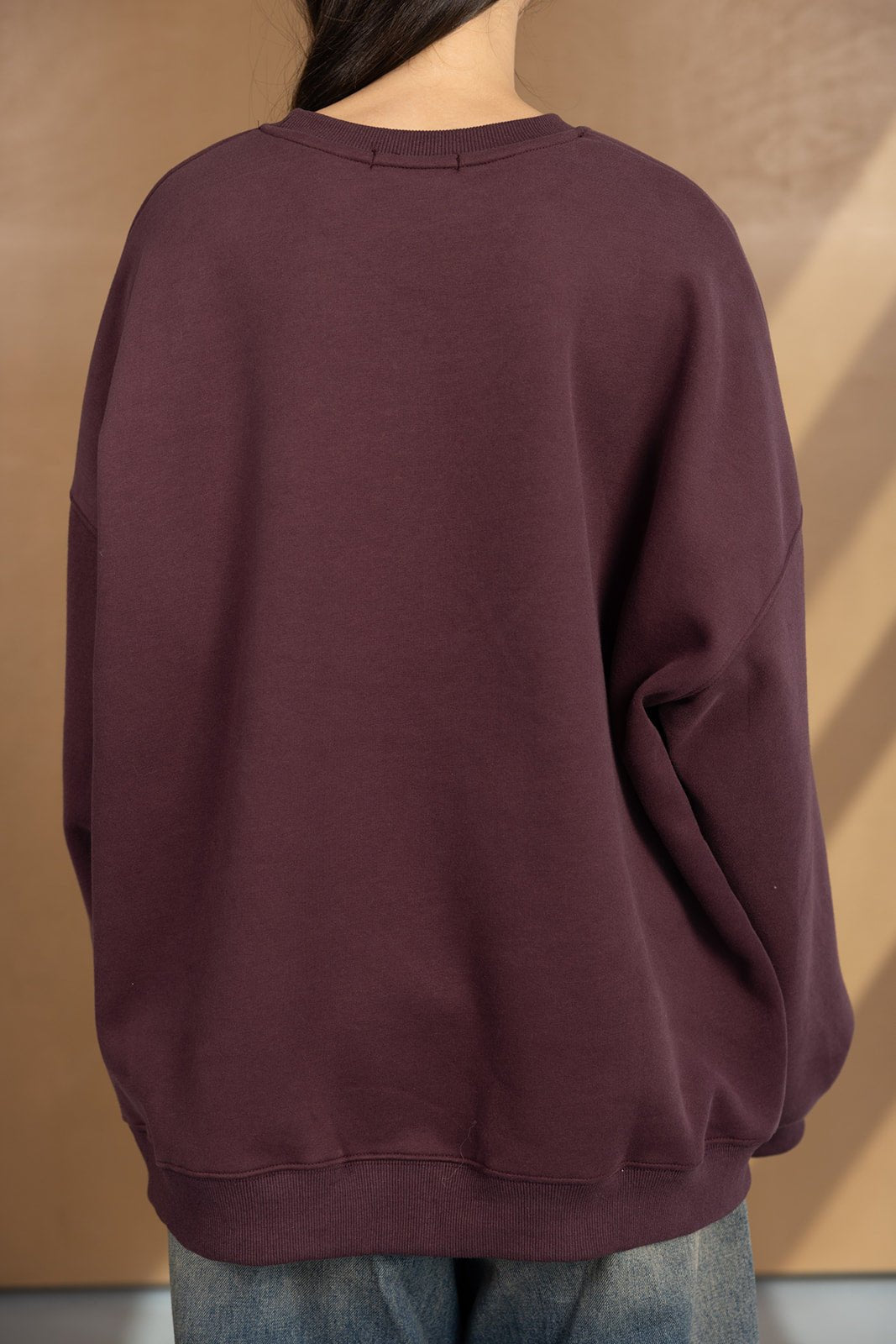 סווטשירט בורדו לנשים עם שרוולים ארוכים בגזרה רחבה, צילום מאחור על רקע חום