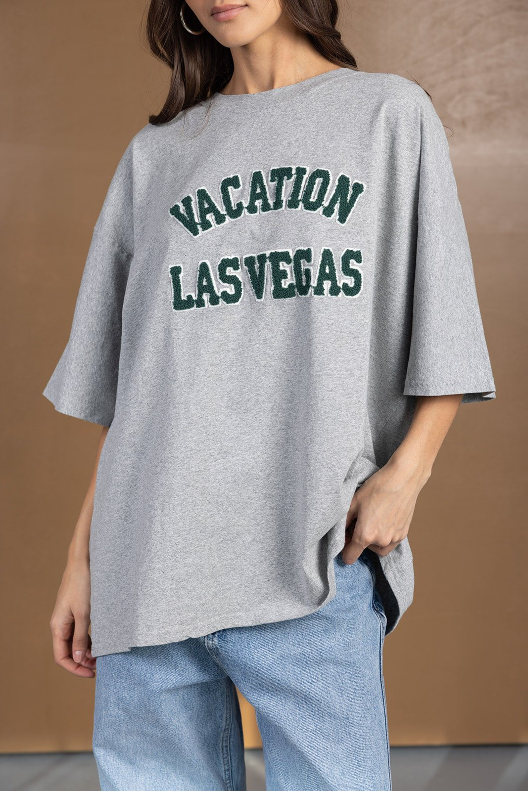 אישה לובשת חולצת טי שירט אפורה עם כיתוב VACATION LAS VEGAS, אופנת רחוב לנשים