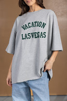 אישה לובשת חולצת טי שירט אפורה עם כיתוב VACATION LAS VEGAS, אופנת רחוב לנשים