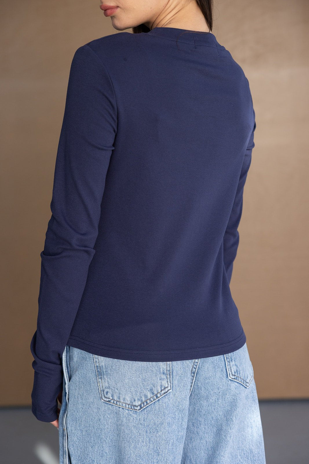 אישה עם חולצת שרוול ארוך כחולה ומכנסי ג׳ינס קצרים בגזרה רחבה, אופנת נשים צעירה