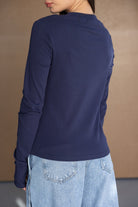 אישה עם חולצת שרוול ארוך כחולה ומכנסי ג׳ינס קצרים בגזרה רחבה, אופנת נשים צעירה