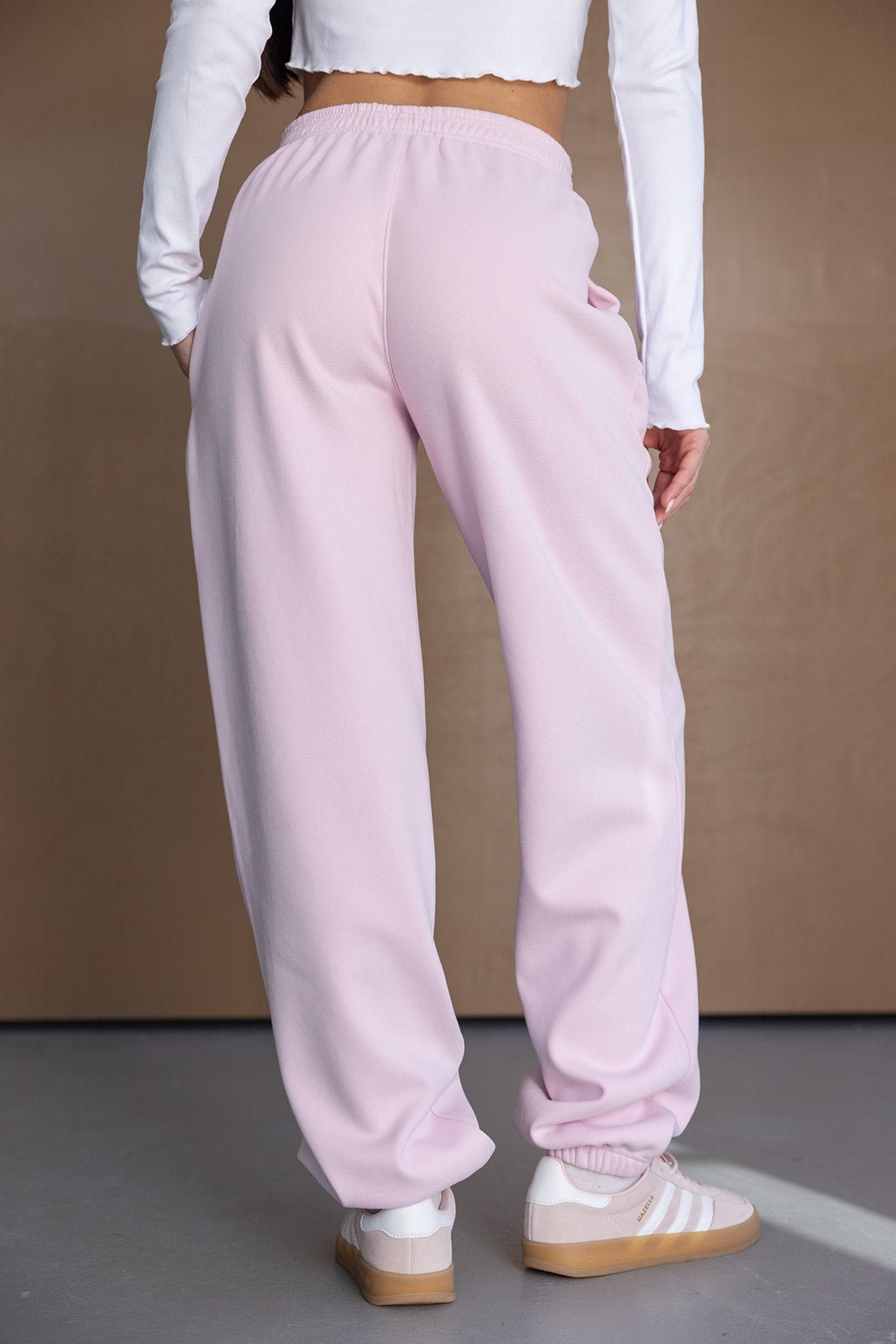 מכנסי טרנינג ורודים לנשים, גזרה רחבה, מבד נעים, עם חולצה לבנה ארוכה ונעלי סניקרס